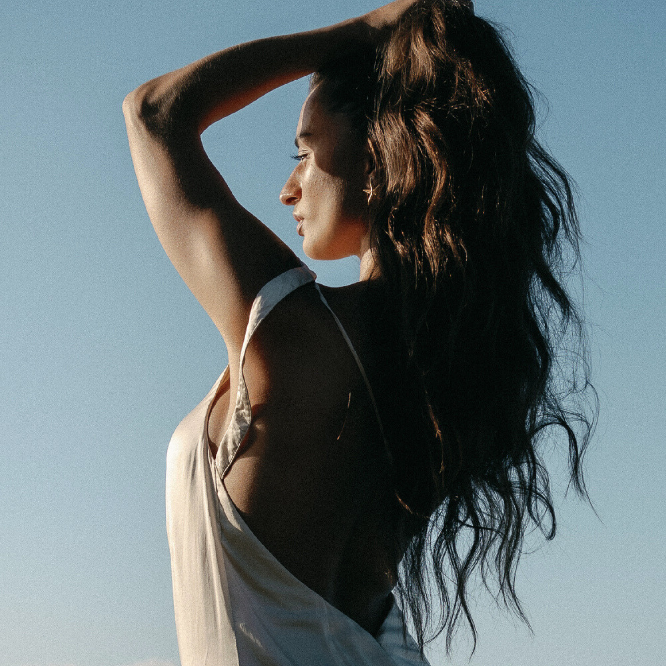 Woman with long dark hair against a clear blue sky